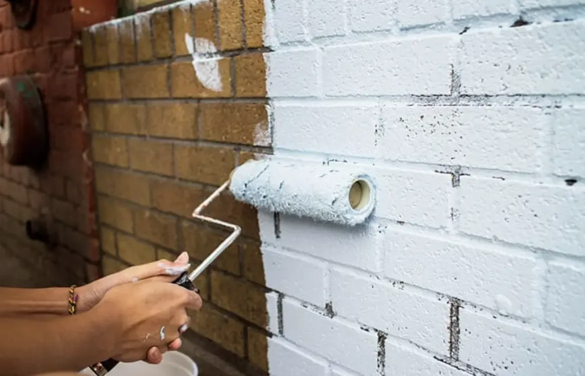 Application au rouleau d'une peinture blanche microporeuse sur un mur en briques