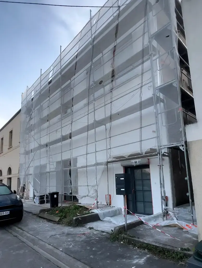 Façade ancienne sous échafaudage après application de la sous-couche tramée