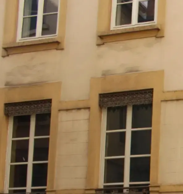 Façade ancienne avec fenêtres profondément encastrées dans un mur épais
