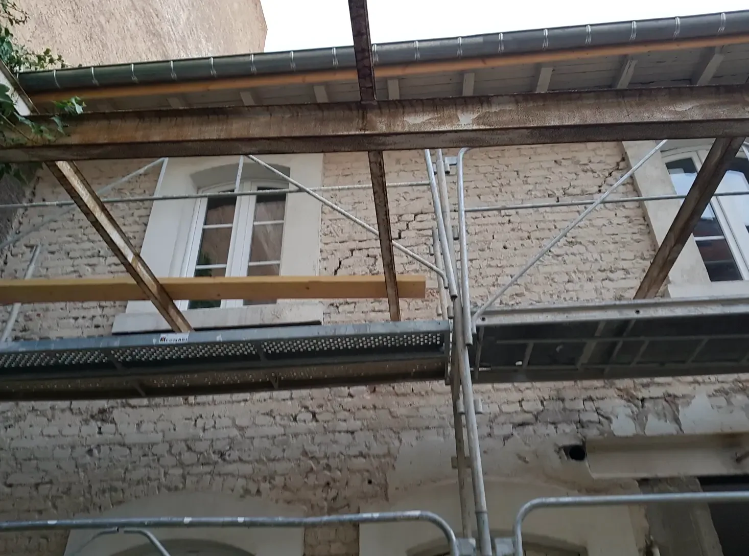 Façade décrépie laissant apparaître les briques et la maçonnerie anciennes