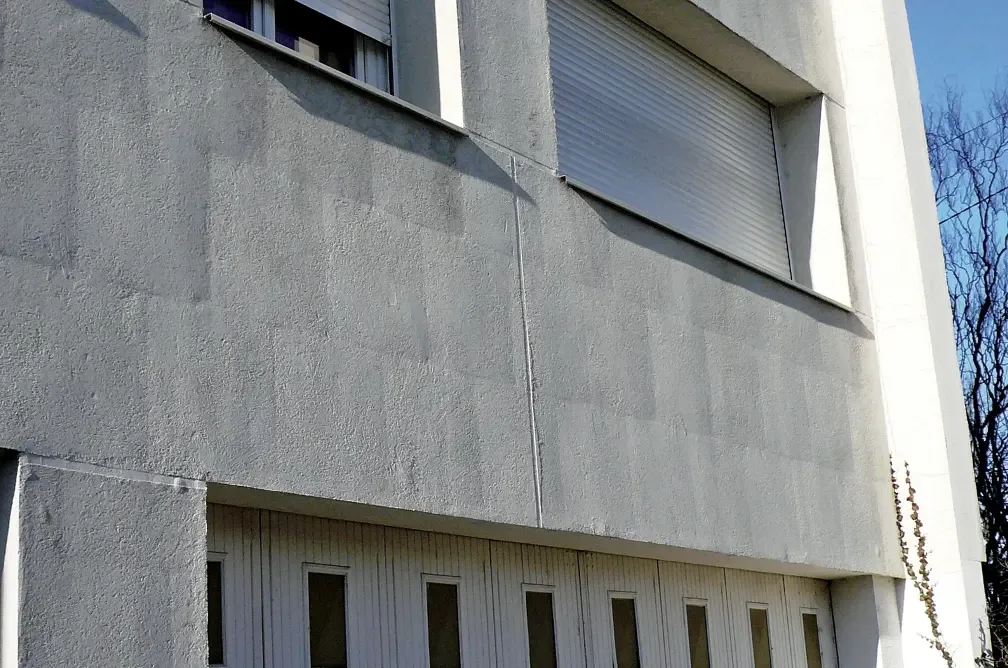 Fissures dessinant les joints des panneaux isolants sous l'enduit