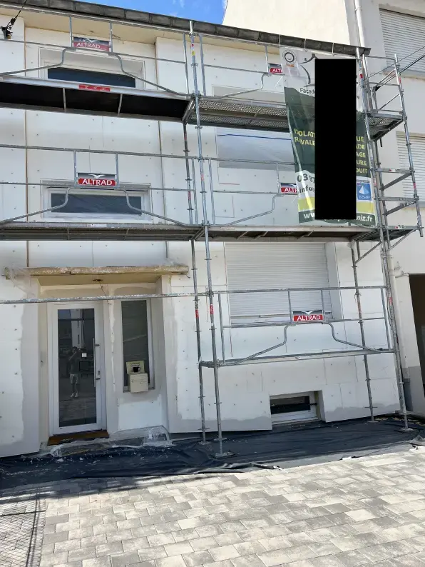 Chantier d'isolation thermique extérieure avec panneaux blancs et échafaudage