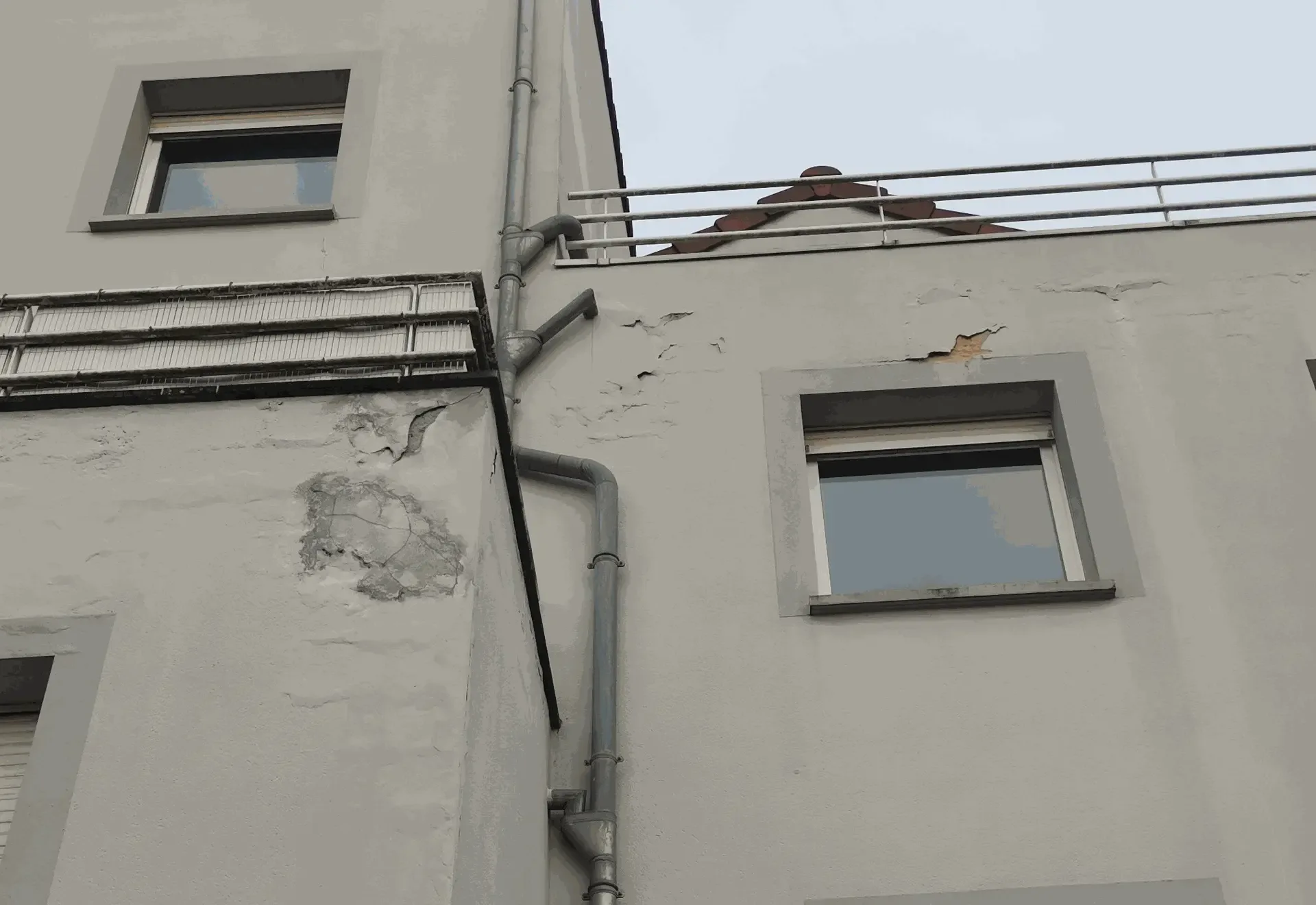 Peinture de façade fortement décollée sous un balcon