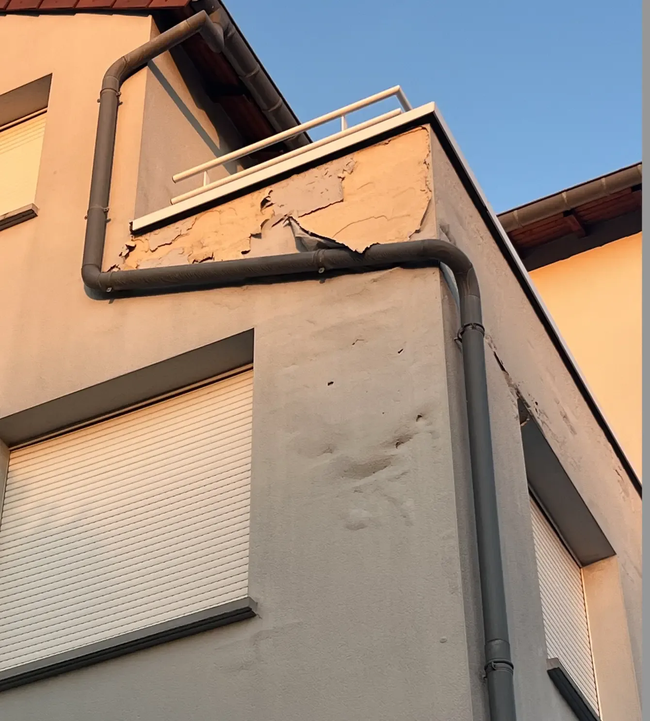 Peinture de façade décollée en larges plaques sur un acrotère