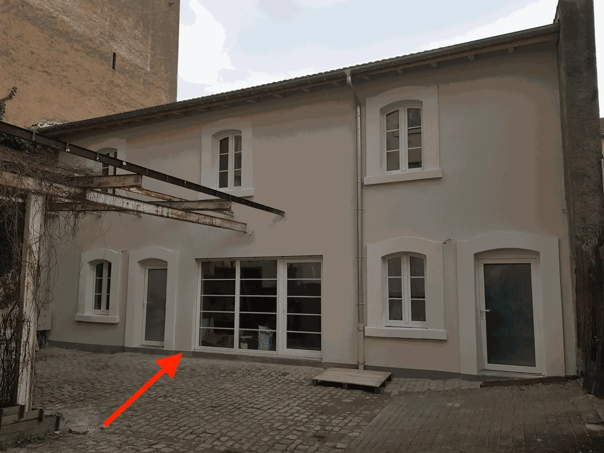 Bande hydrofuge grise séparant le crépi du sol dans une cour