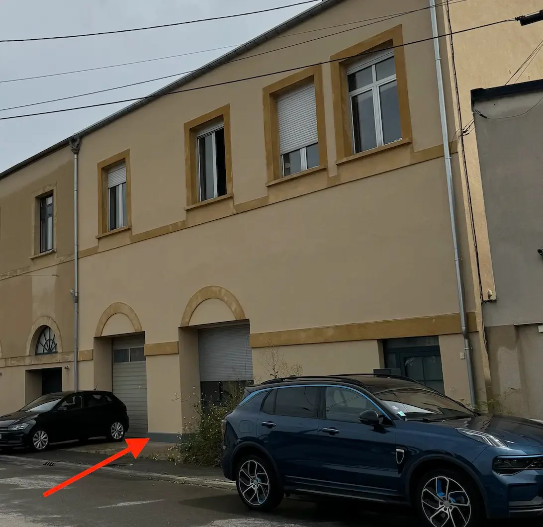 Bande hydrofuge grise visible au pied d'une façade côté rue